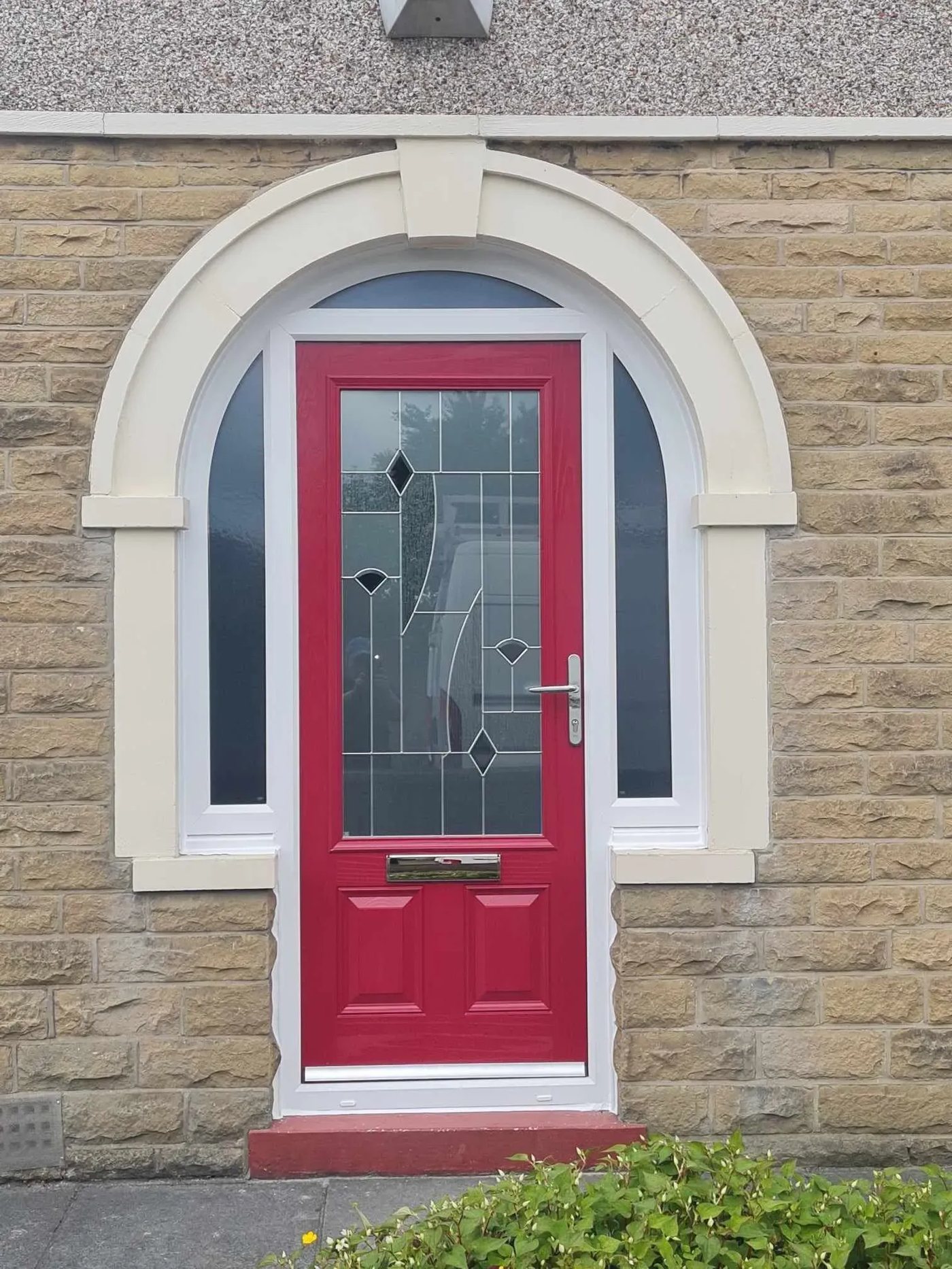 Red composite front door with leaded glass panel, arched stone porch